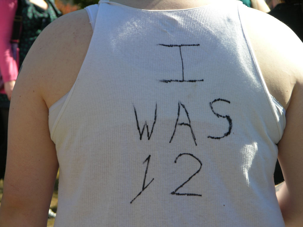 "I was 12" T-shirt message from Minneapolis demonstration (Wikimedia Commons)